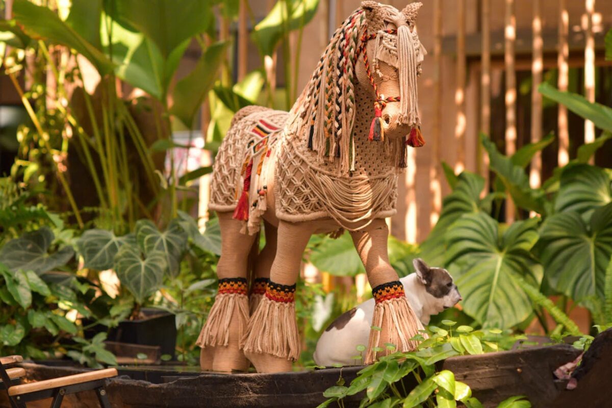 Macramé horse sculpture in a vibrant garden with a small French Bulldog.